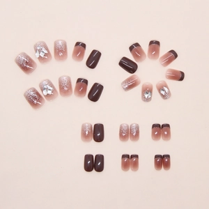 Detail of red-brown press-on nails with glitter gradients and 3D rhinestones decor
