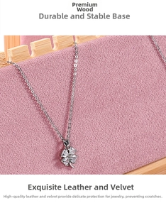 Detail shot of a clover pendant displayed on a pink velvet and wooden jewelry stand