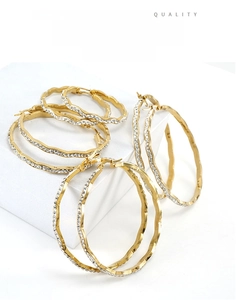 Detailed view of wave-shaped 18K gold-plated hoop earrings with micro-pave crystals