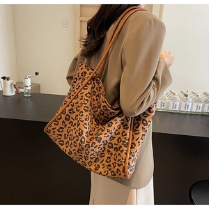 Detail view of large leopard print tote bag with leather straps on a female model
