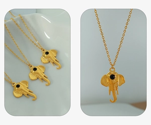 Macro view of golden elephant pendant with black bead eye and delicate O-chain
