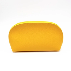 Detail of a bright yellow cosmetic bag showing textured lychee leather and curved zipper top