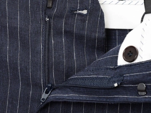 Detailed macro view of the YKK metal zipper and white stripes on linen blend pants
