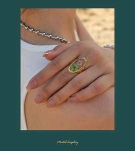 Detail of a vintage resin ring with green and pink dried flowers on a gold band