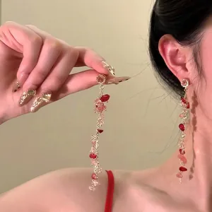 Detail of pink and red beaded long tassel earrings with golden metal chains for summer