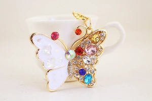 Detailed close-up of colorful crystal butterfly keychain with rhinestones and white shell wings