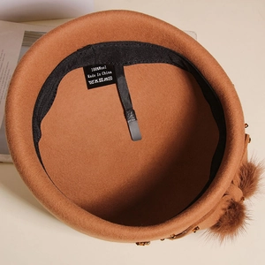 Detail view of 100% wool brown beret featuring genuine mink fur ball and bead accents