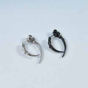 Macro shot of punk claw stud earrings in polished silver and black metallic finishes