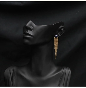 Macro detail of natural dark pearl earring with elegant long gold chain tassels
