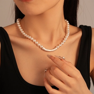 Detail of minimalist pearl choker with a sleek matte silver curved tube on the collarbone