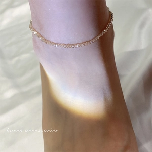 Elegant beaded anklet with champagne crystals on a foot resting on silk fabric