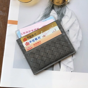 Slim grey woven sheepskin card holder with multi-slot design on fashion magazine