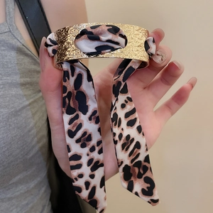 Detail of golden textured wide cuff bracelet with a leopard print silk ribbon insert