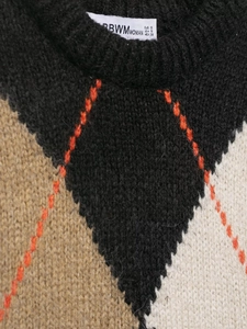 Detail of V-neck knit vest with argyle pattern and inner size label with brand branding