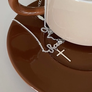 Detail of high-polished silver cross pendant necklace on elegant ceramic tableware