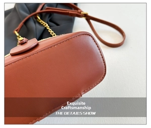 Detailed close-up of brown leather handbag base with premium stitching and gold chain