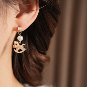 Detail of gold-plated rocking horse earring with white pearl and sparkling zircons