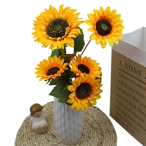 Artificial five-head sunflowers in a white textured vase with decorative props