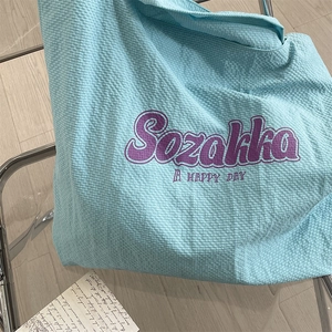 Détail du sac cabas bleu clair à texture gaufrée avec lettrage artistique Sozakka