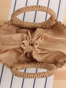 Minimalist straw woven tote bag with drawstring lining shown from a top-down view