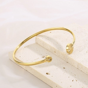 Detail of adjustable C-shaped gold bangle with zircon stone and sunburst engraving