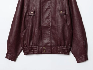 Detailed close-up of the burgundy PU leather jacket with elastic waist and metal snap buttons