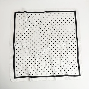 Detailed flat lay of white square silk scarf with black polka dots and border
