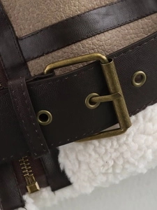 Close-up of brown pebbled leather texture and off-white faux fur lining on a jacket