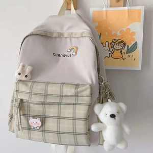 Detail of off-white checkered canvas backpack with cute plush bear and rabbit charms