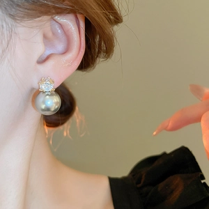 Vue rapprochée de boucles d'oreilles perles gris-bleu avec cristal et monture dorée