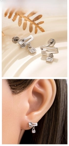 Close-up of spoon and fork stud earrings with a heart lock pendant on a tray and model