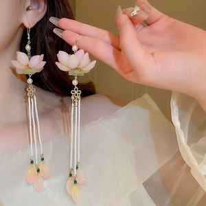 Detail of pink lotus flower earring with white bead tassels worn by a female model