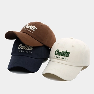 Close-up of three cotton baseball caps with Create NEW LIFE embroidery in brown and navy