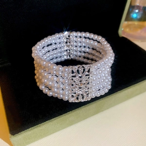 Detail of multi-layer white pearl bracelet with silver-tone rhinestone clasp on black velvet