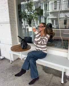 Street style view of long sleeve striped Polo shirt paired with wide leg denim jeans