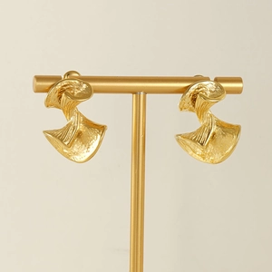 Detailed shot of gold irregular spiral earrings with hammered texture on a metal stand