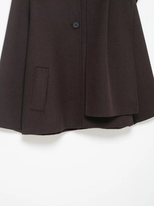 Detail of dark brown wool coat hem featuring a large button and a flat welt pocket