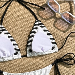 Detail of white ribbed bikini top with black lacing, metal eyelets and heart-shaped pads