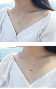 Detailed view of gold and silver starfish pendants worn by a model at the beach