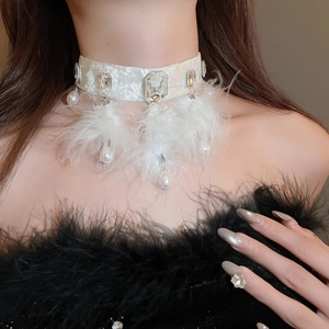 Detail of white velvet choker with crystal inlay, feathers and hanging pearl pendant
