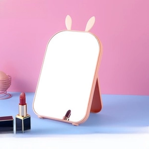 Pink rabbit-ear desktop makeup mirror with a foldable stand and compact square design