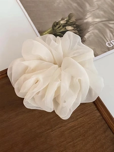 Close-up of white organza scrunchie with layered pleats on a dark wooden tray