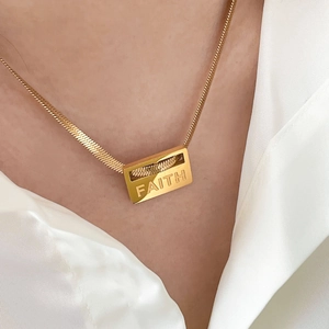 Detail of gold herringbone necklace featuring a square pendant engraved with Faith