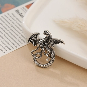 Vintage silver dragon brooch with detailed wings and scales on a ceramic tray