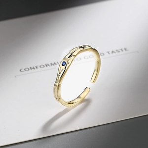 Bague dorée ajustable avec pierre de zircon bleu sur fond de papier élégant
