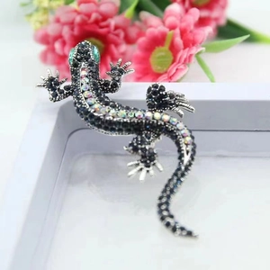 Detailed view of vintage lizard brooch with black crystals and green emerald eyes
