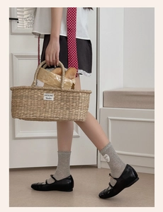 Detail of grey mesh socks with heart patch paired with black Mary Janes and straw bag