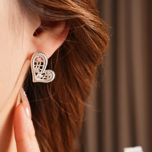 Detail of silver heart earring with hollow woven design and clear zircon stones on ear