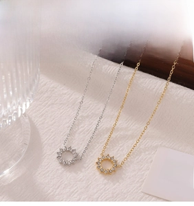 Detail of silver and gold sun flower zircon pendant necklaces on soft knit background