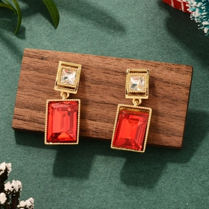 Detail of vintage gold earrings with red rectangle gems on dark wood display